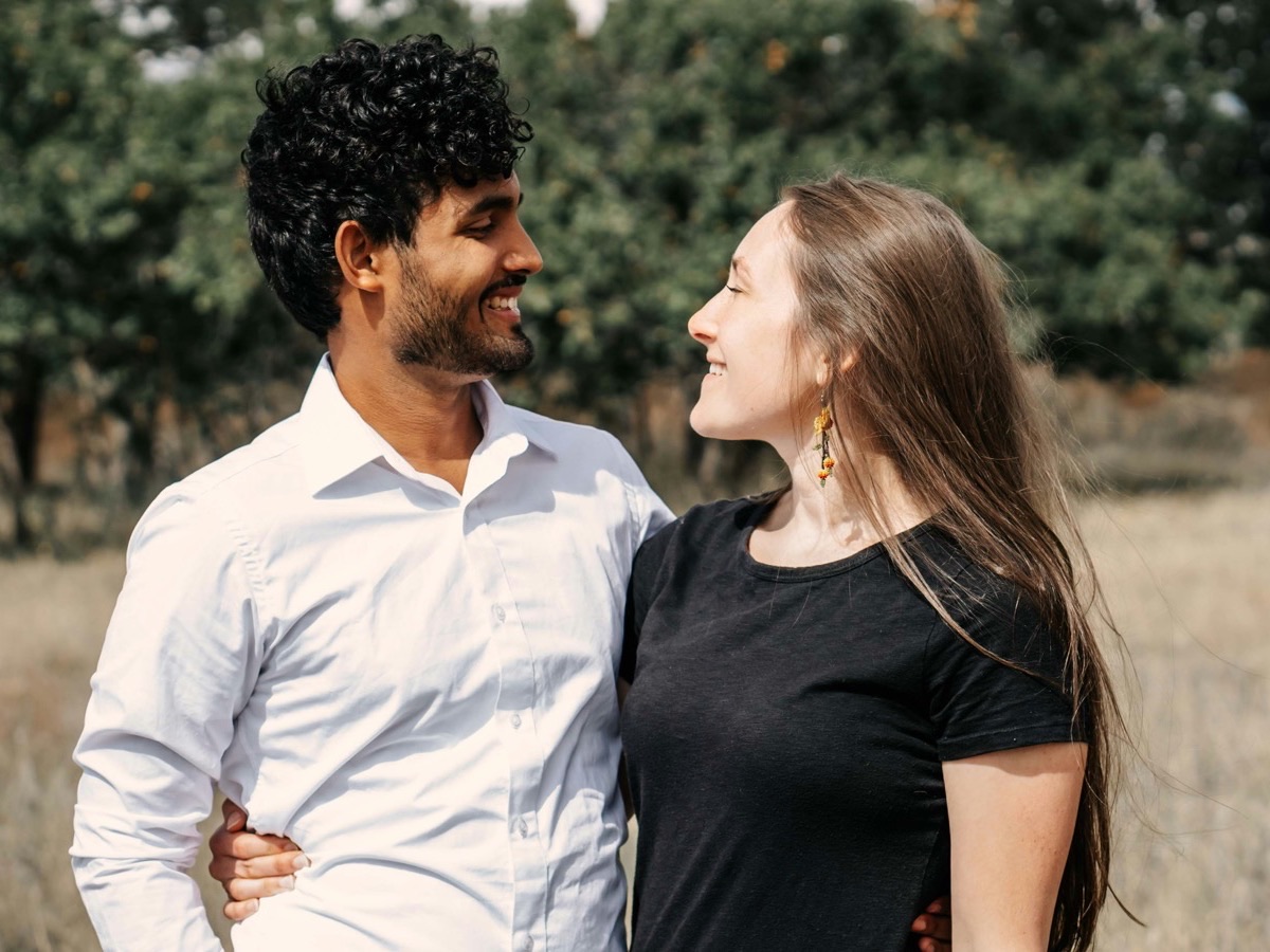 A couple standing close together outdoors, looking at each other